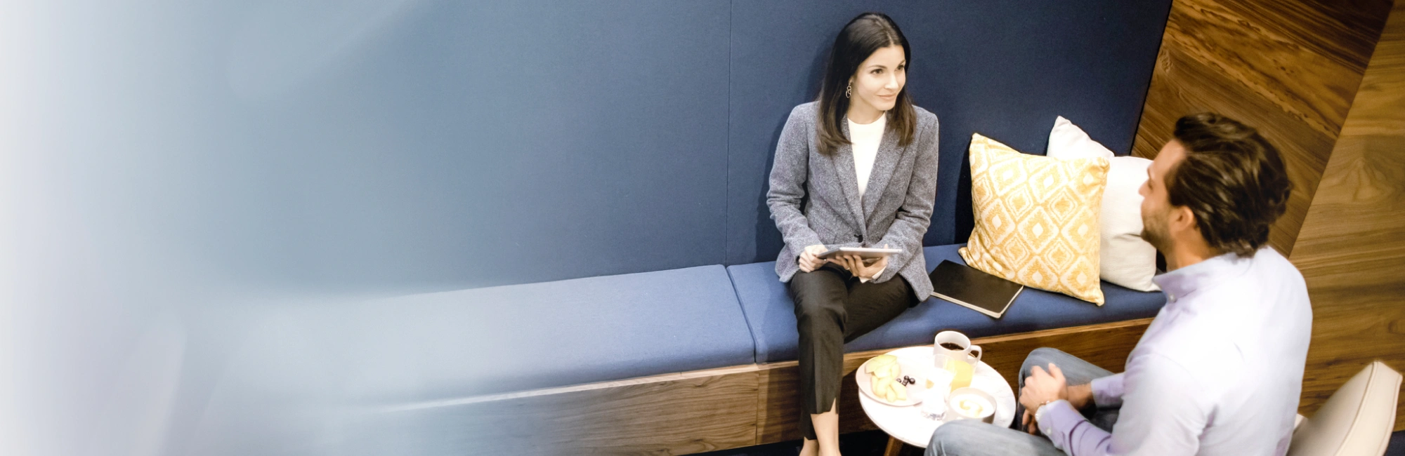 Business conversation in contemporary workplace seating area featuring built-in bench and soft furnishings