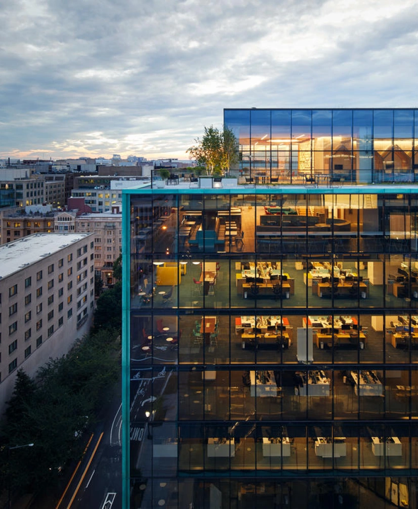 Contemporary commercial office tower featuring floor to ceiling windows and rooftop terrace at sunset