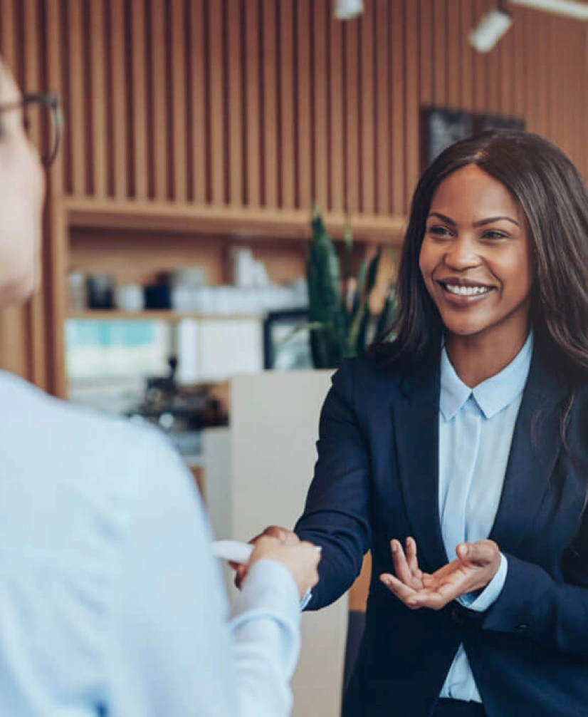 Confident professional woman engaging in client interaction and exchanging business card indoors