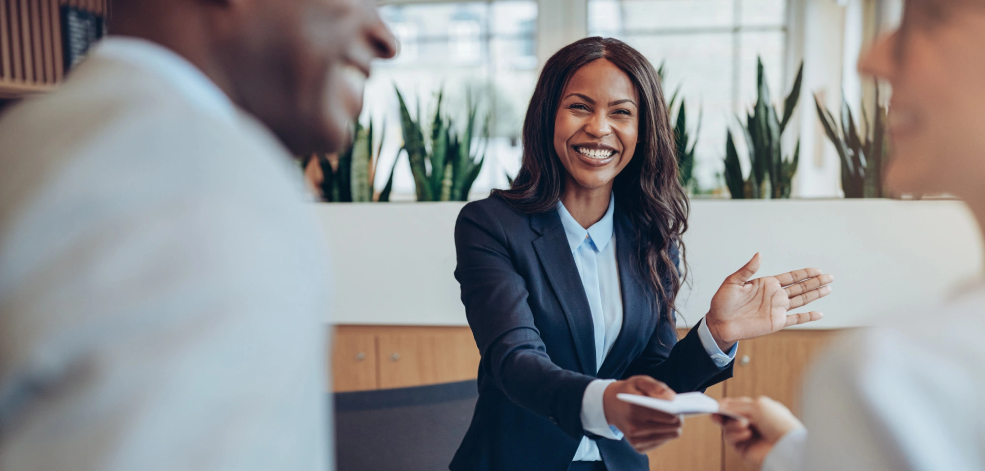 Confident professional woman presenting paperwork to colleagues in collaborative workplace setting