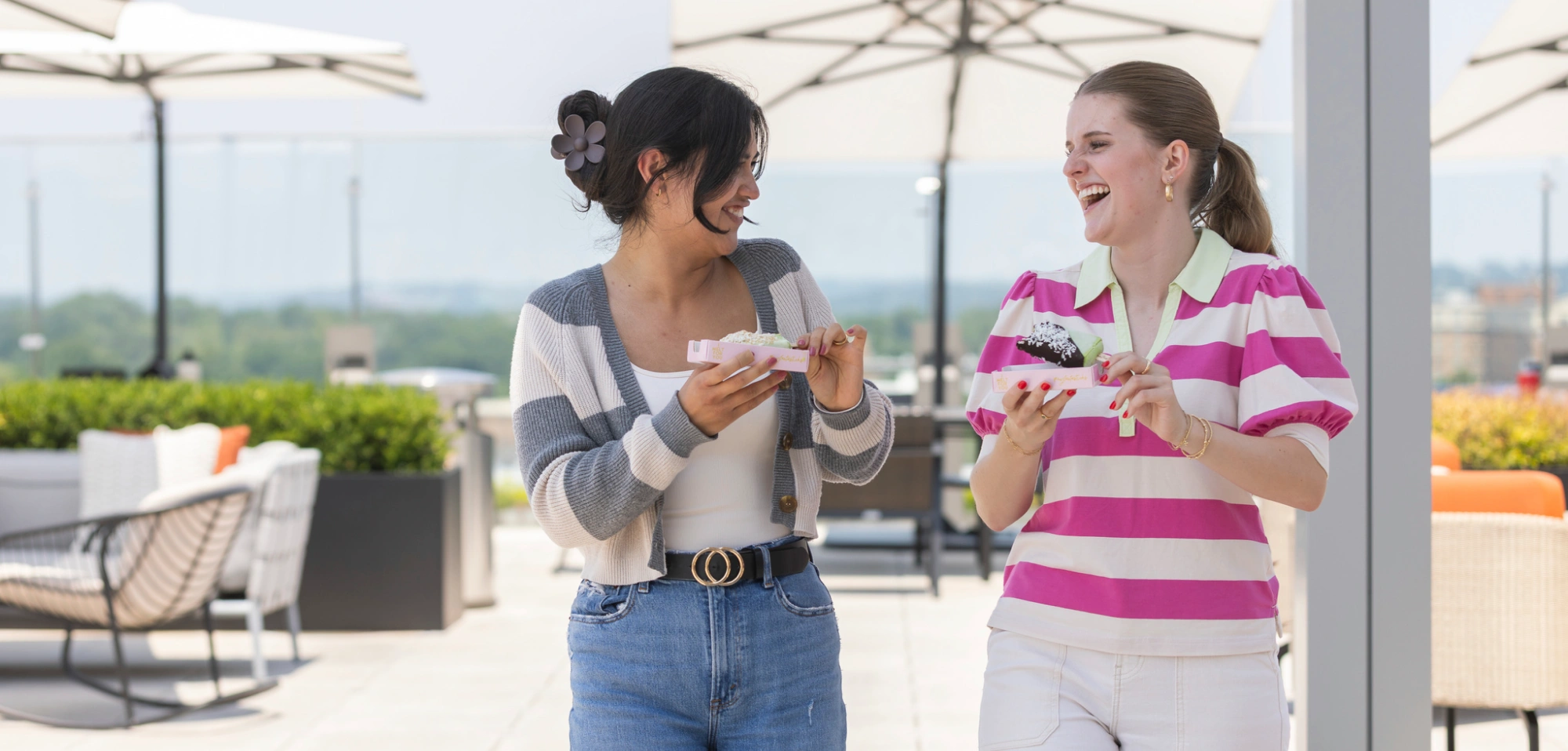 Friends sharing pastries outdoors on a modern rooftop patio with city views