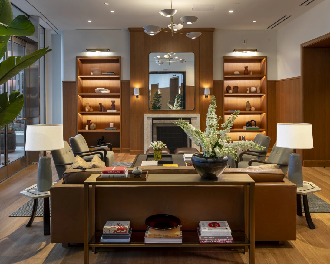 Elegant modern lounge with fireplace, built-in shelving, neutral seating, and warm ambient lighting