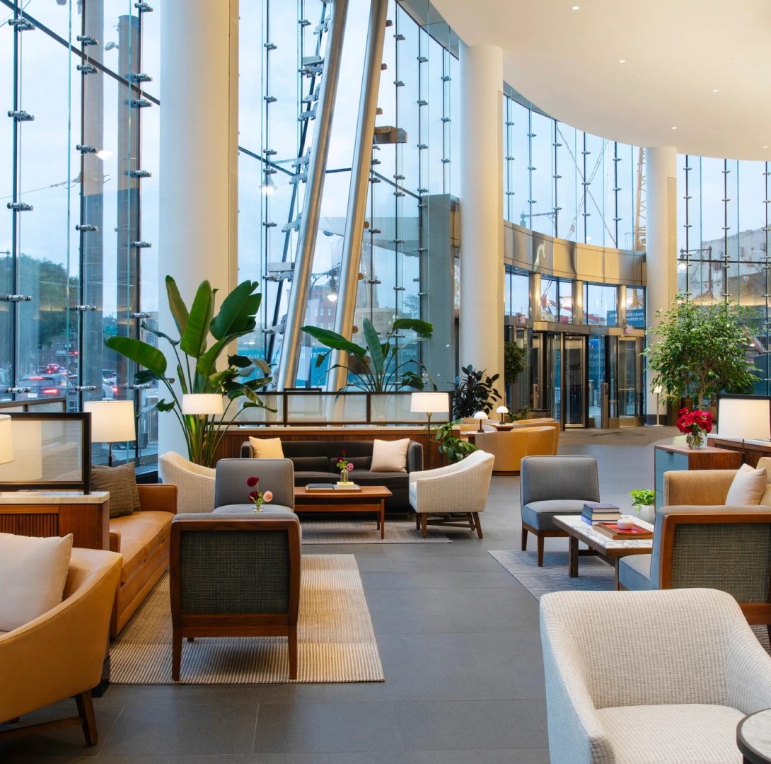 Modern glass lobby lounge with comfortable seating indoor plants and natural daylight