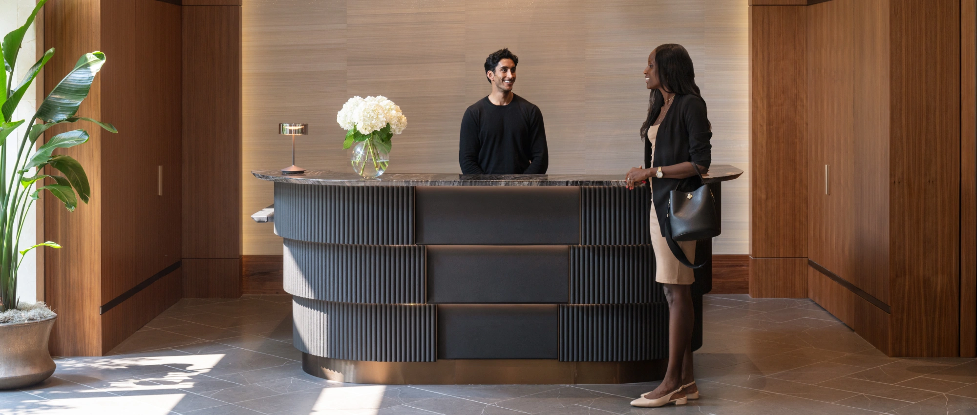 Stylish corporate welcome area featuring warm wood finishes and friendly front desk service