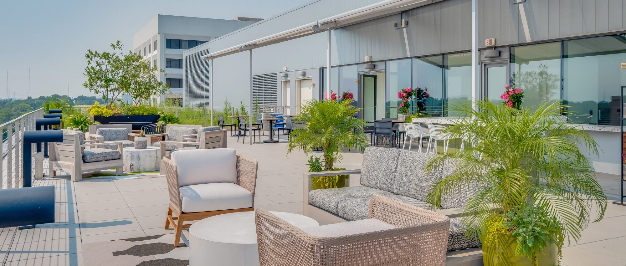 Modern corporate rooftop patio with comfortable seating, landscaped plants, and bright open-air design