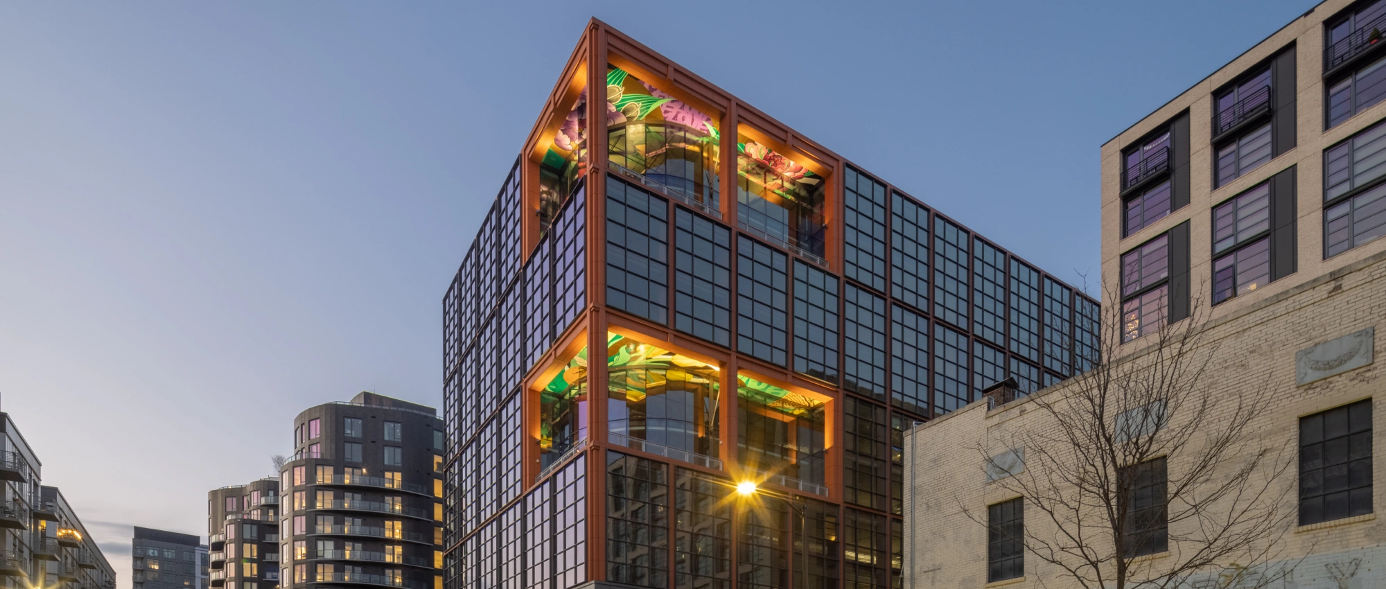 Modern urban office tower showcasing colorful rooftop artwork expansive windows and surrounding city architecture