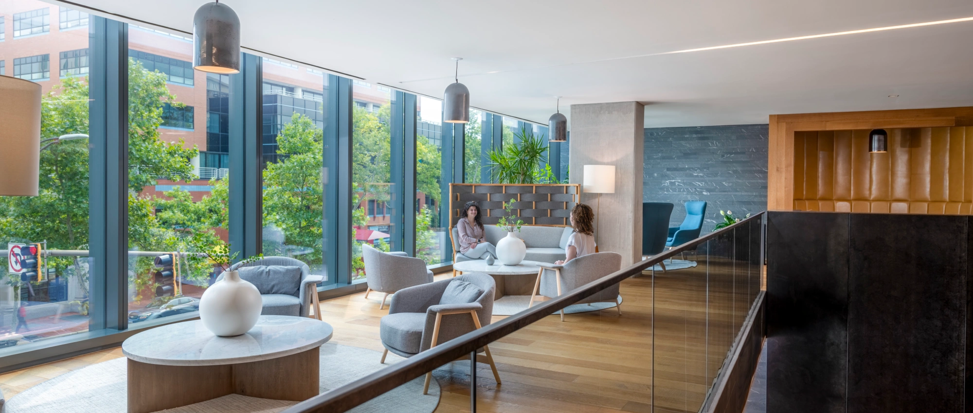 Contemporary office or residential common area featuring floor to ceiling windows warm wood floors and casual seating