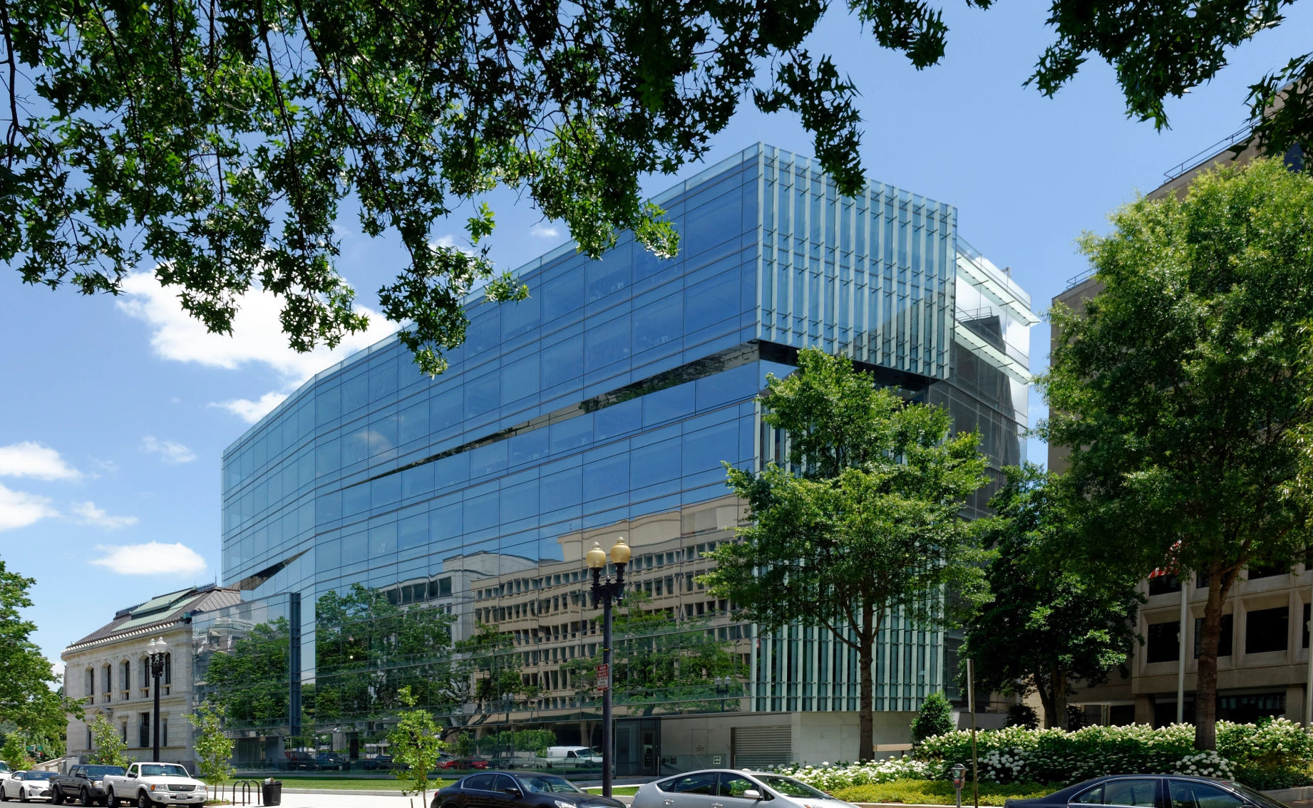 Modern urban architecture emphasizing transparency and clean horizontal lines, integrated with a landscaped streetscape