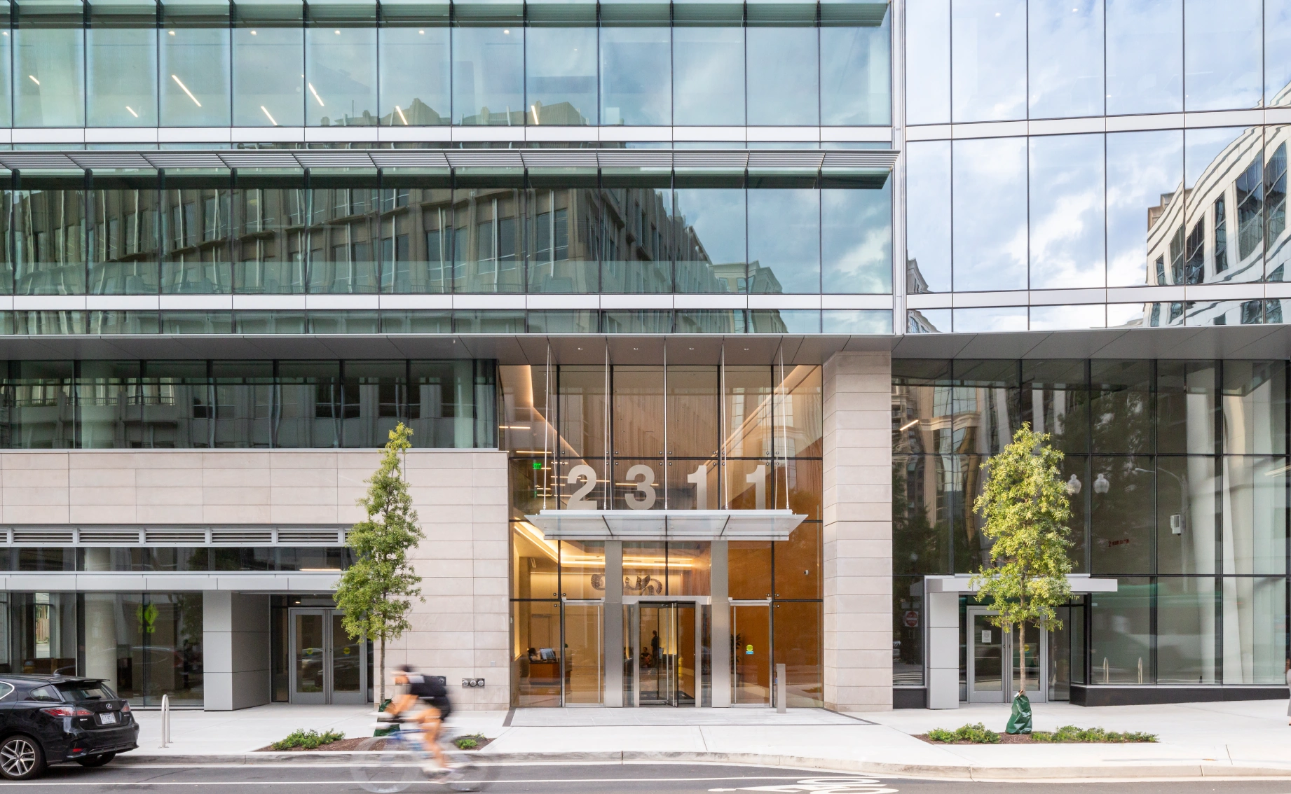 Contemporary corporate headquarters facade featuring large glass panels, illuminated entry, and city reflections