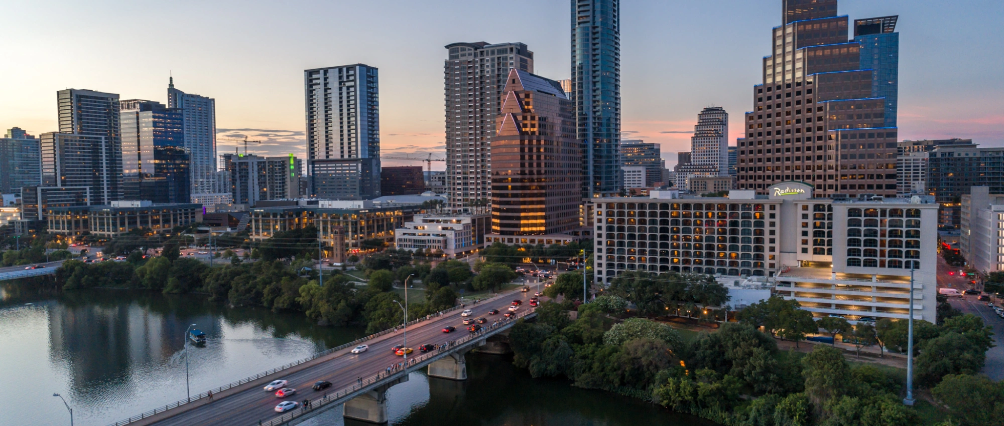 Austin Texas cityscape featuring modern skyscrapers waterfront reflections and busy evening bridge traffic