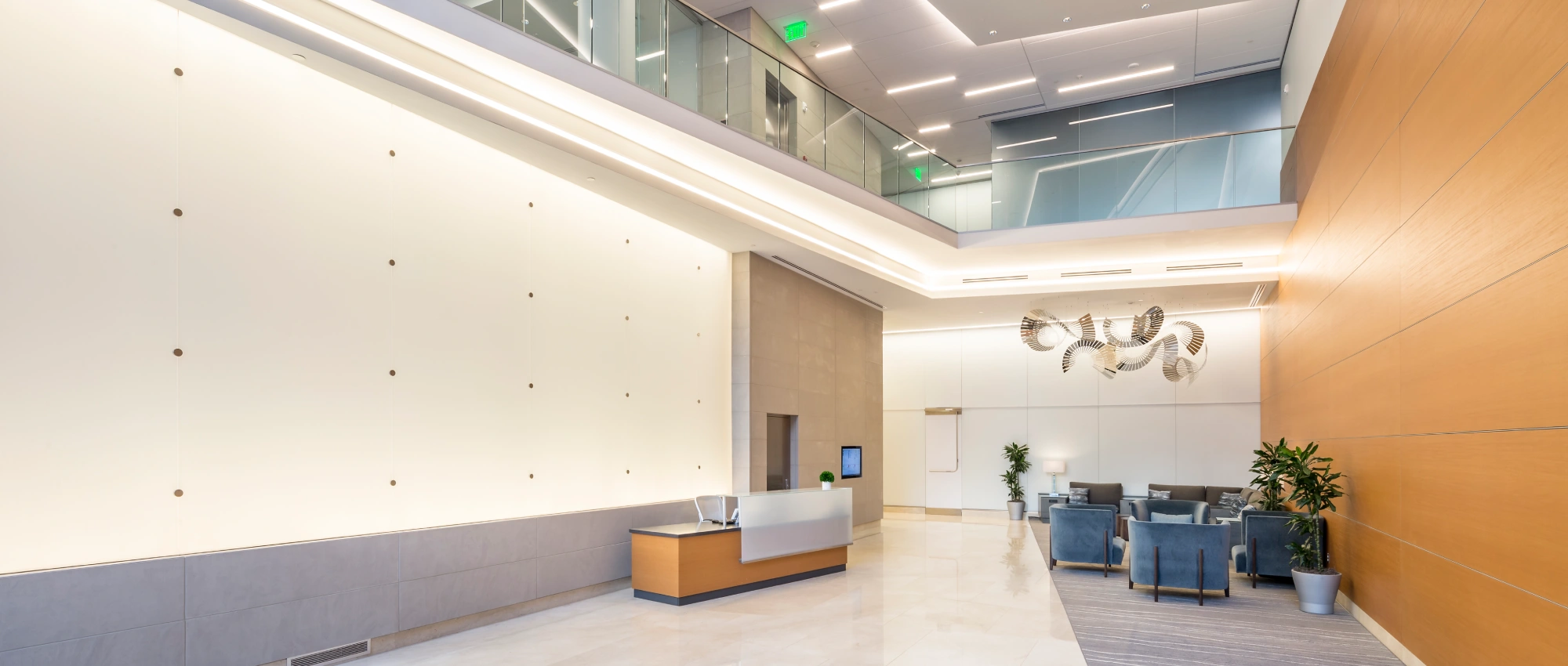 Upscale commercial building interior showcasing spacious lobby, modern reception desk, integrated lighting, and refined finishes