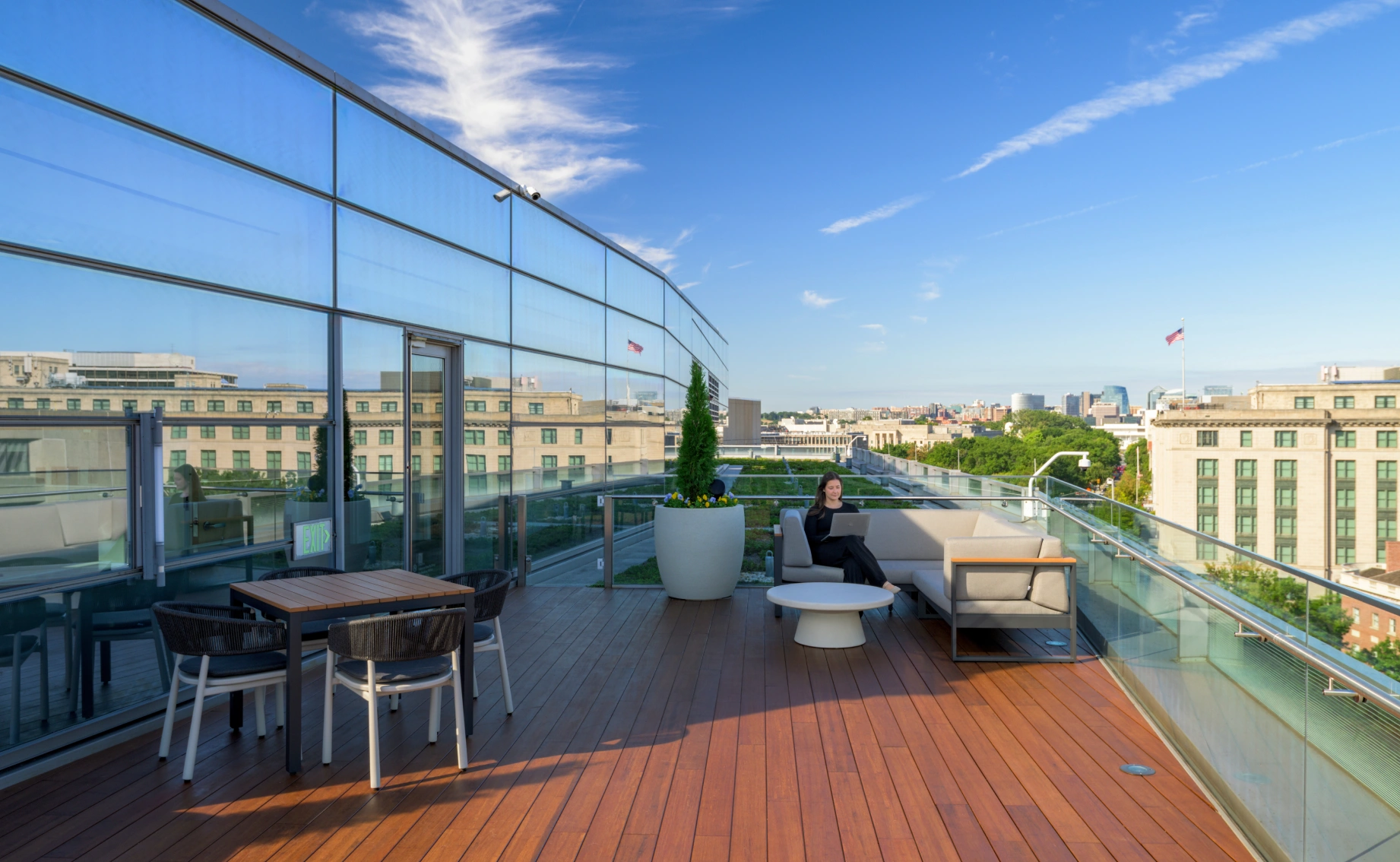 Contemporary rooftop amenity space featuring lounge furniture, planters, and reflective glass façade of an adjacent building