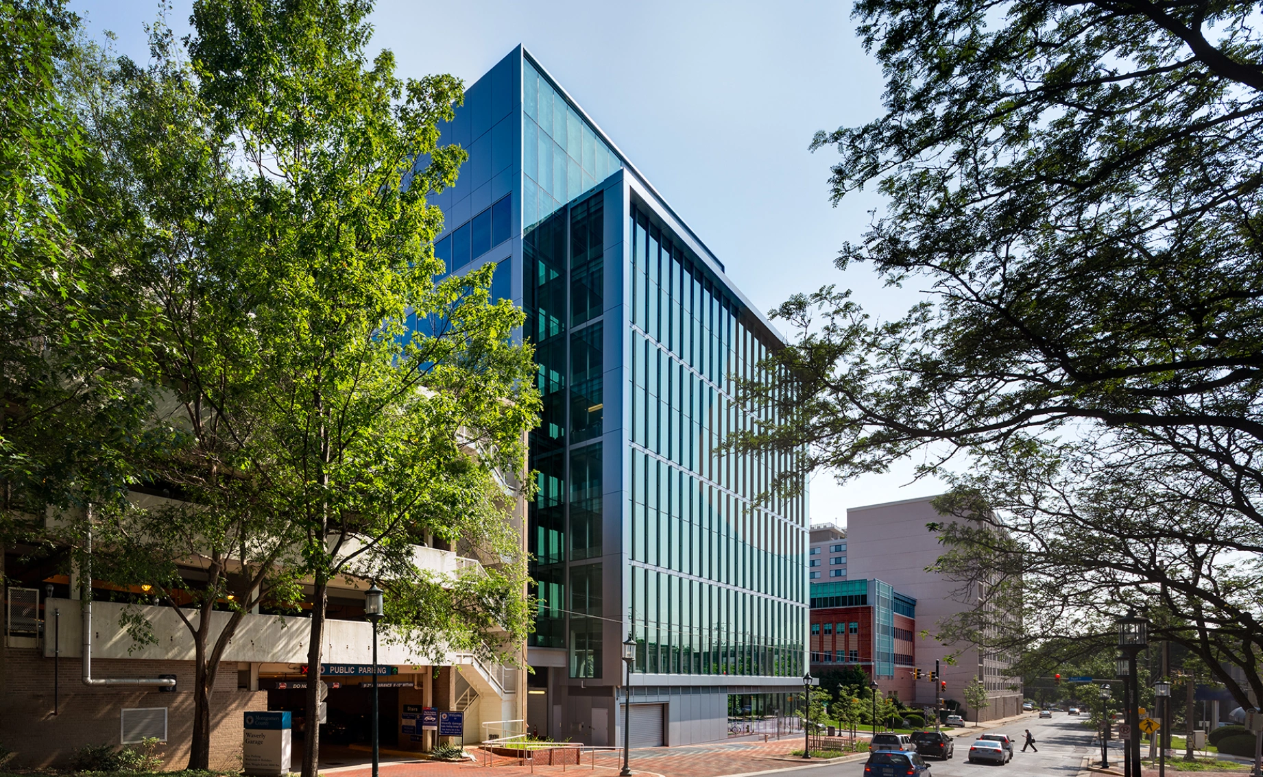 Contemporary urban office tower with reflective glass facade greenery sidewalks and surrounding buildings