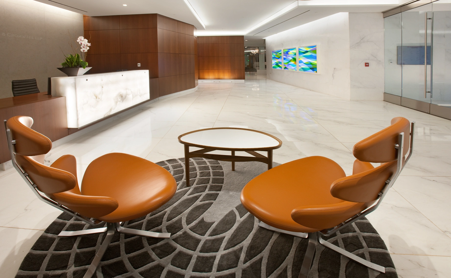 Corporate building lobby featuring sculptural leather chairs, round coffee table, and polished marble surfaces