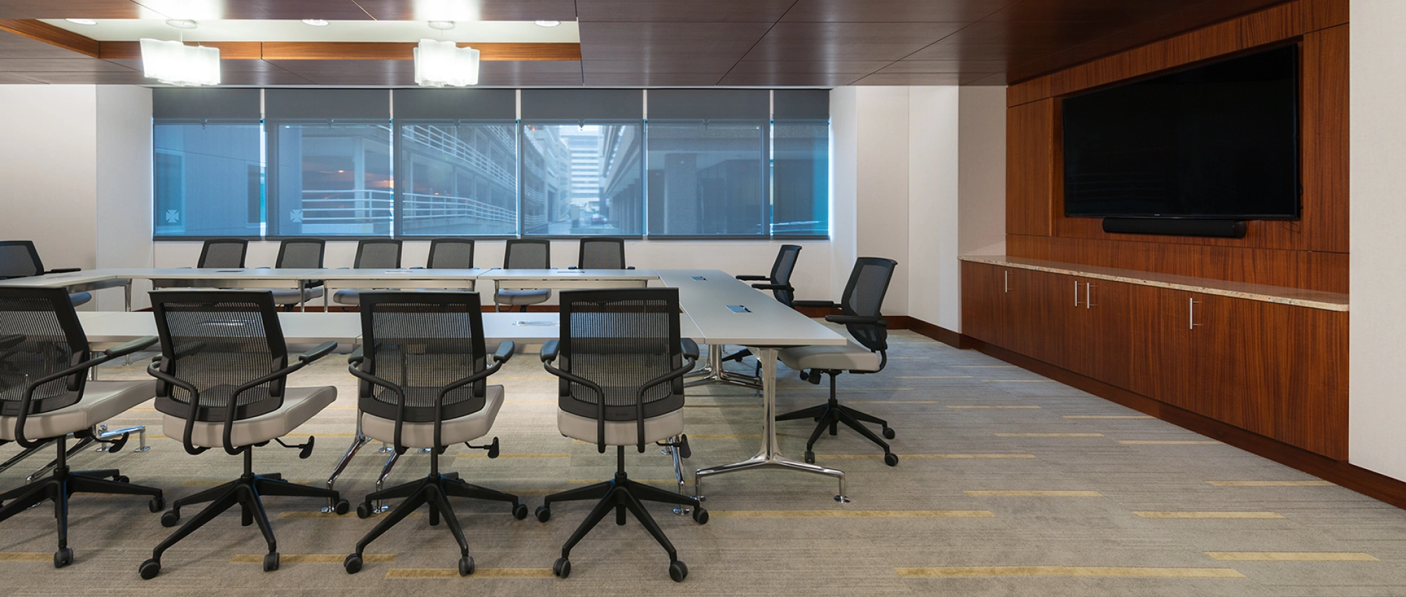 Contemporary corporate boardroom featuring clean lines, neutral tones, large windows, and built-in cabinetry
