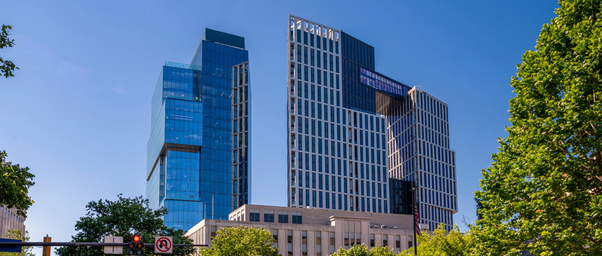 Modern mixed-use development rising above a tree-lined urban setting, showcasing innovative architecture and dynamic massing