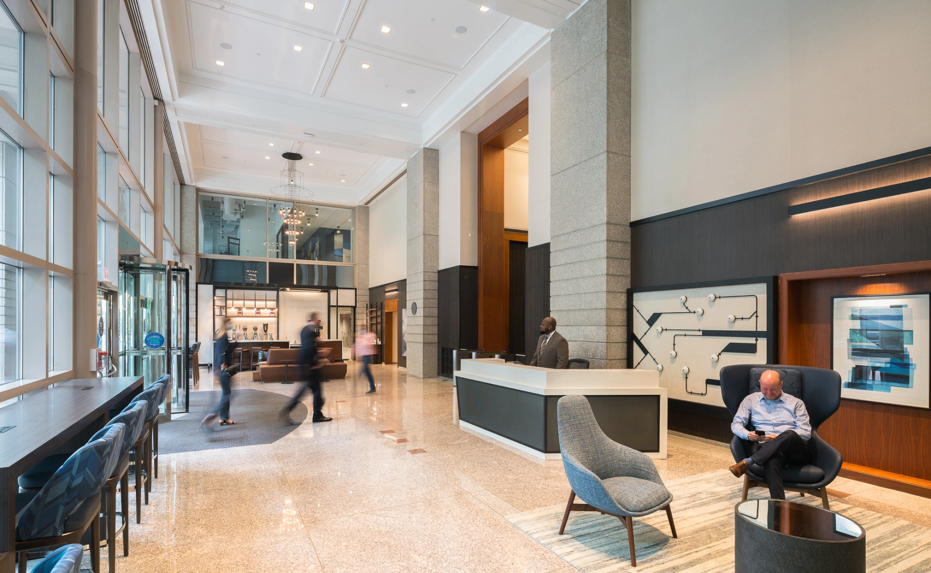 Spacious corporate lobby interior featuring reception area, lounge seating, glass entry doors, and elegant lighting