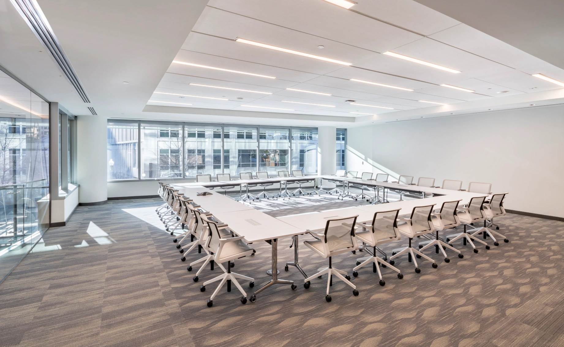 Bright, modern conference room with flexible seating, large windows, and contemporary lighting