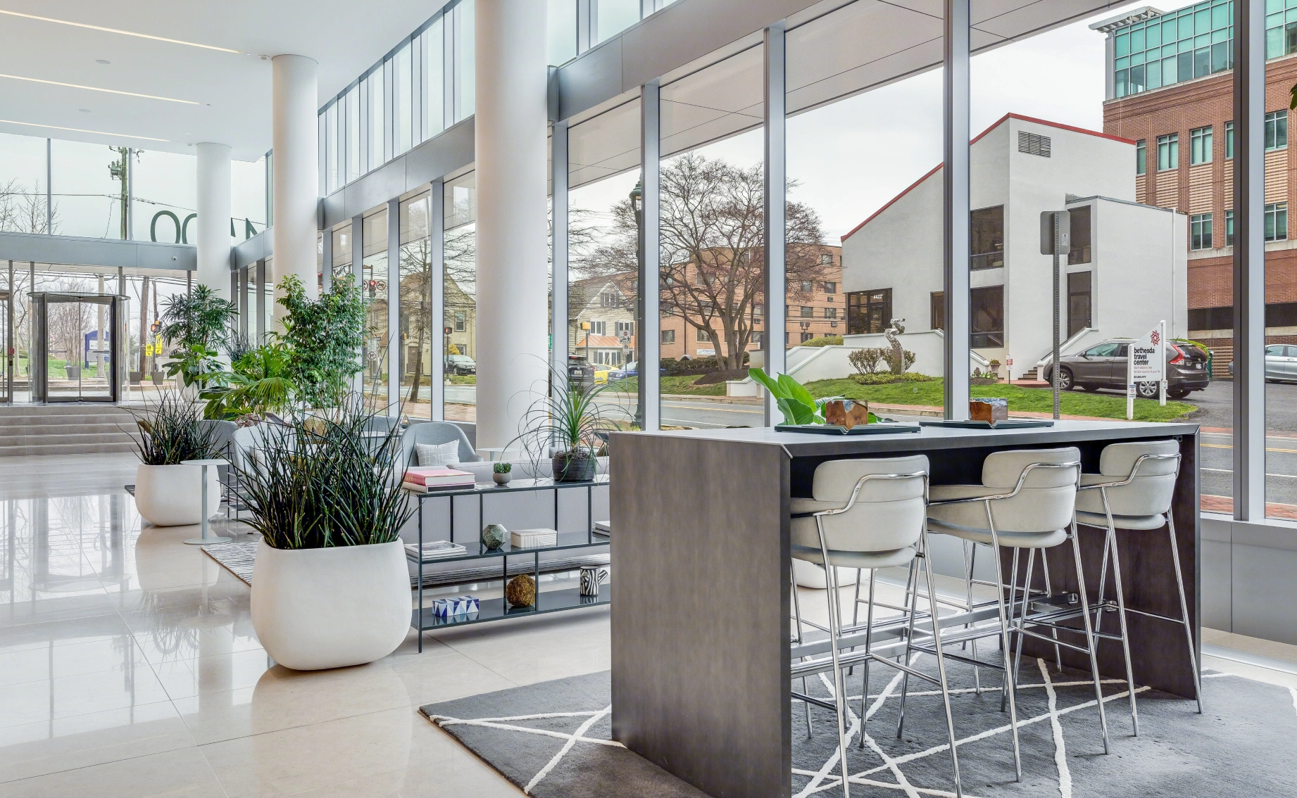 Contemporary corporate lobby interior featuring glass walls polished floors bar seating and landscaped plants