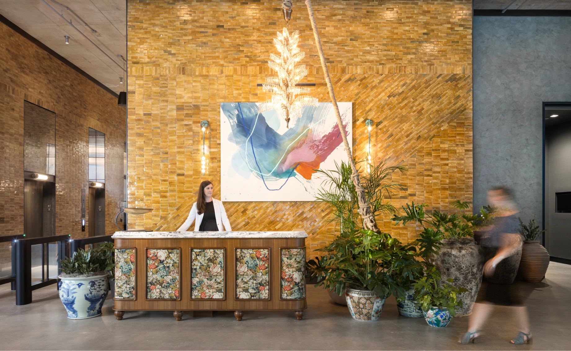 Refined modern reception area with artistic wall décor, layered textures, and a welcoming concierge framed by rich materials and soft lighting