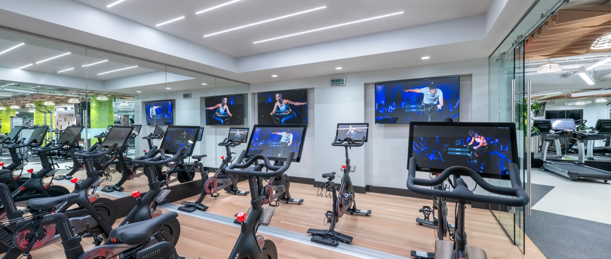 Modern corporate fitness studio featuring interactive spin bikes digital displays and bright contemporary lighting