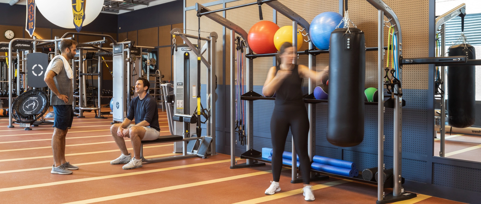 Contemporary wellness center showcasing mixed training activities, from boxing drills to strength and conditioning conversations