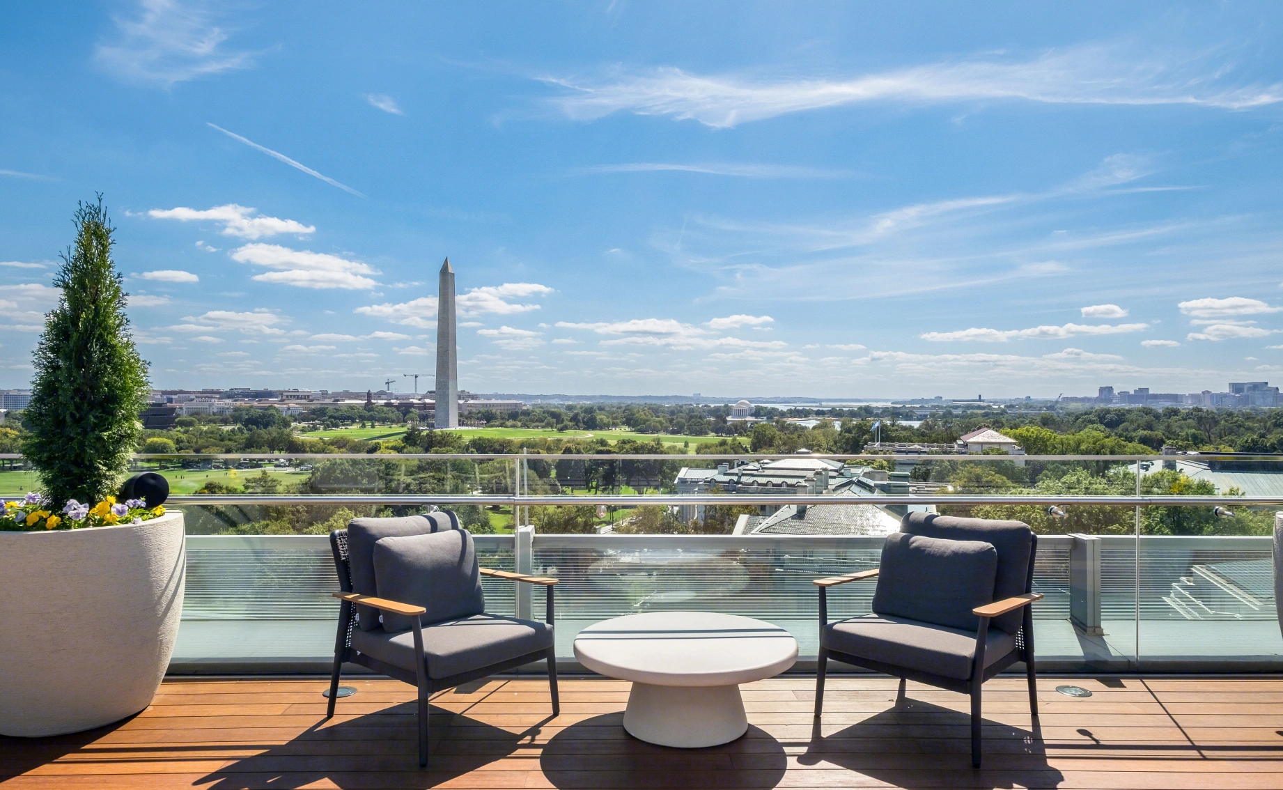 Luxury rooftop amenity featuring comfortable seating, planters, and iconic Washington DC skyline views