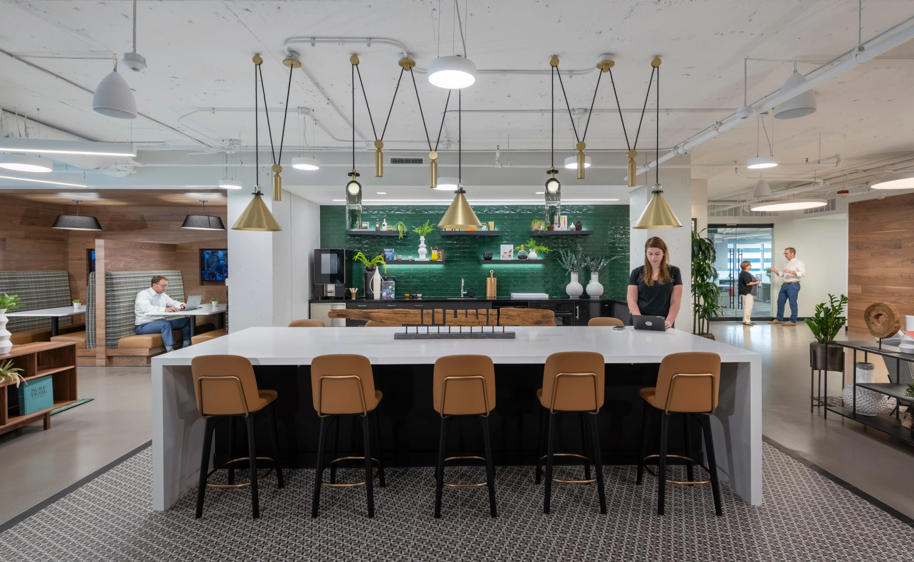 Contemporary workplace amenity space featuring communal island bar stools plants and open layout