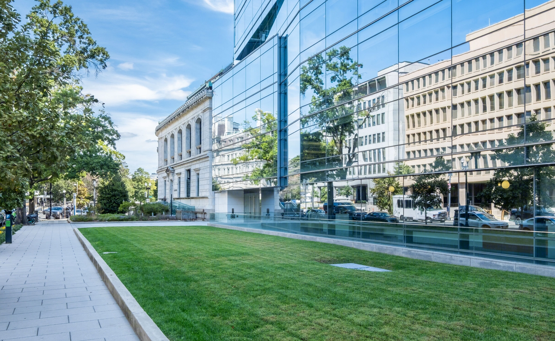 Sleek commercial or institutional building highlighting transparency, clean lines, and contrast between modern and classical city elements