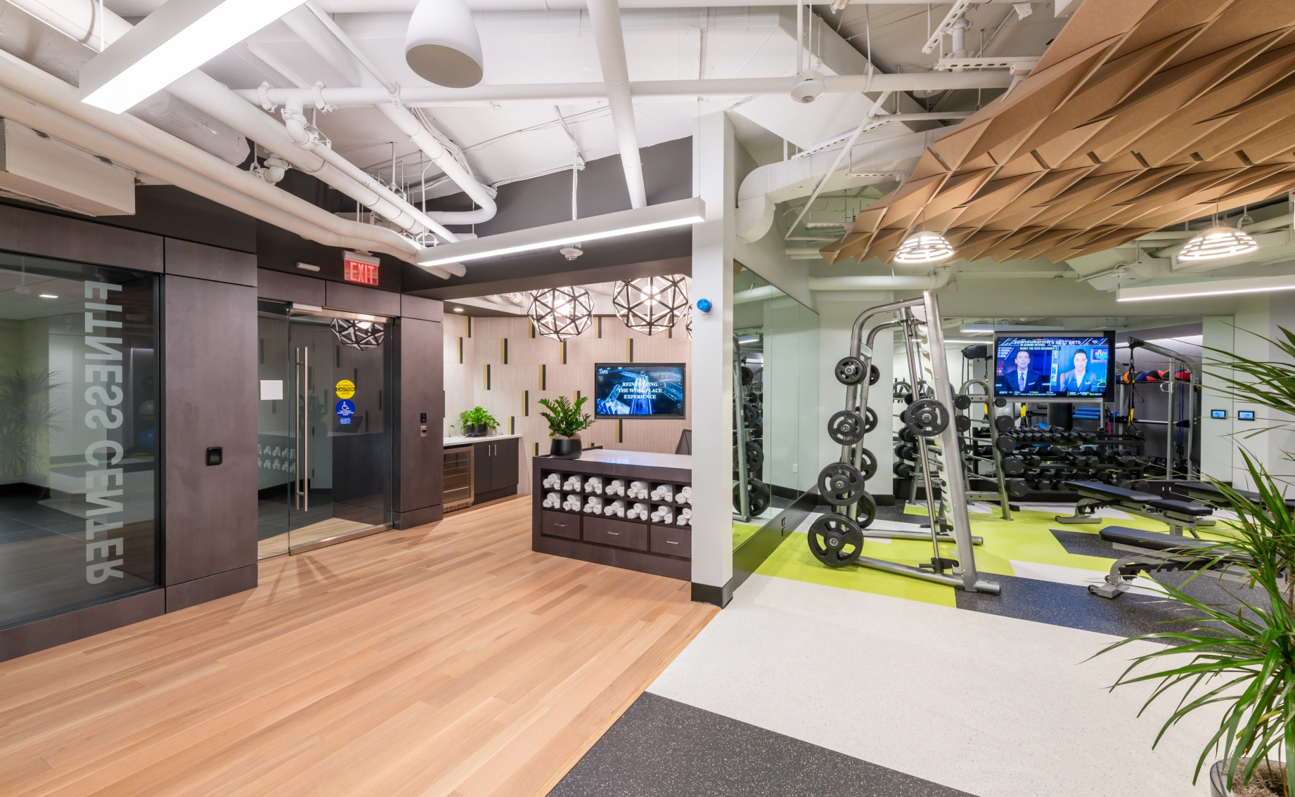 Contemporary apartment fitness center showcasing organized weight racks, cardio zone, wood accents, and open layout