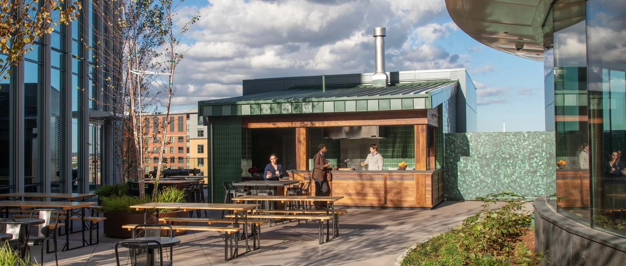 Contemporary rooftop amenity space featuring open air café seating greenery and urban skyline views