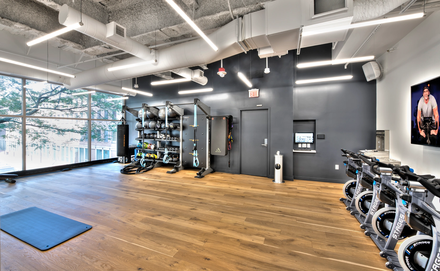 Contemporary workout room featuring stationary bikes, open floor space, strength racks, and large windows