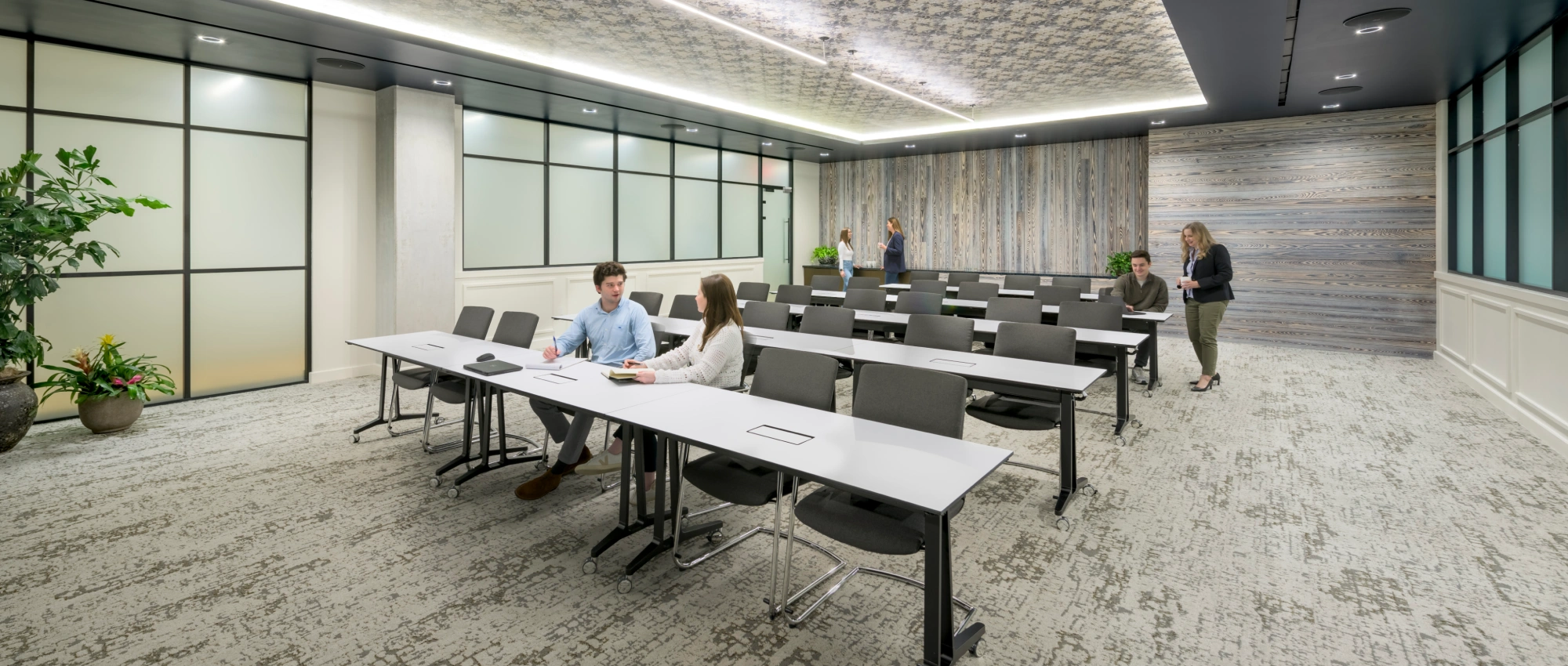 Contemporary conference classroom featuring movable desks glass walls soft lighting and team discussions