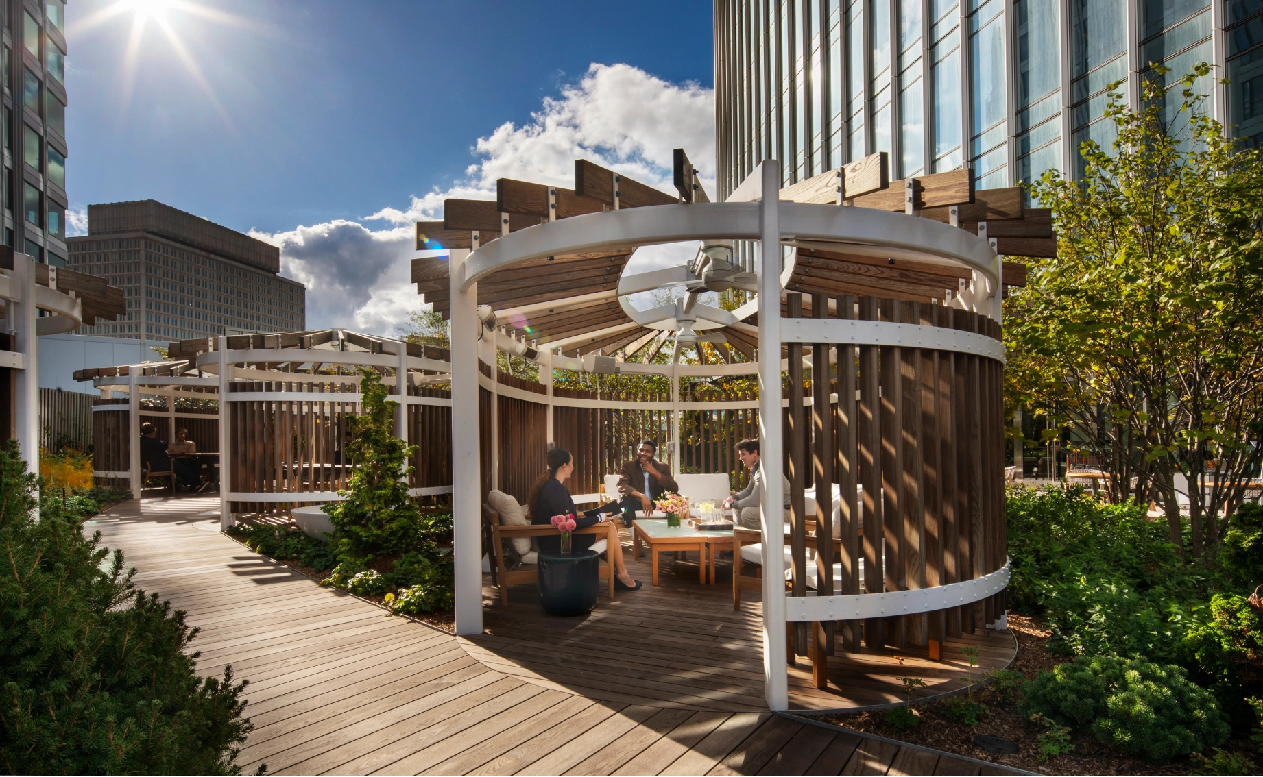 Modern outdoor workspace designed with circular wooden pavilions, comfortable seating, and skyline views for informal meetings and social gatherings