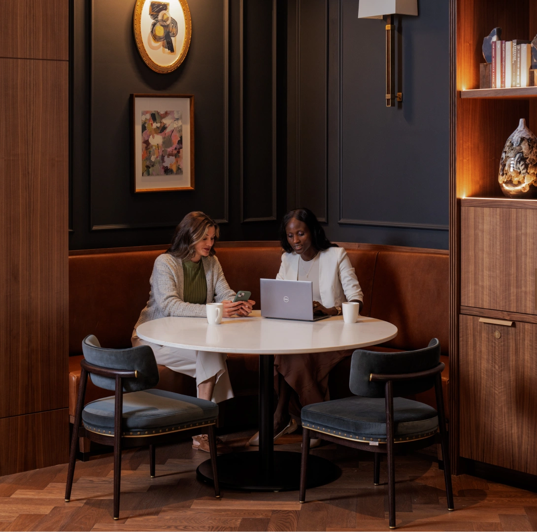 Modern workplace lounge featuring colleagues meeting over laptop coffee in stylish built-in booth