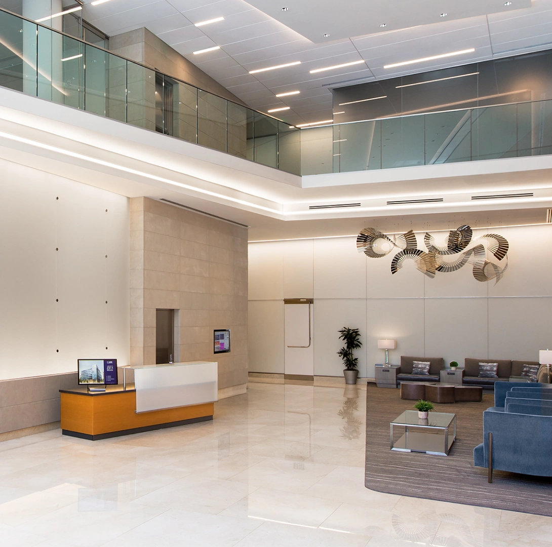 Sophisticated corporate atrium with polished stone floors, modern reception desk, and sculptural lighting
