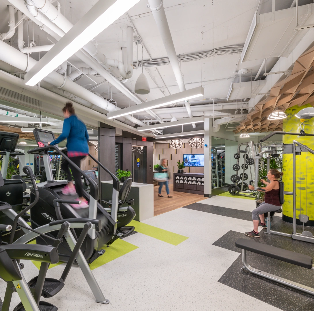 Modern fitness center with cardio machines strength training equipment and an open industrial-style ceiling