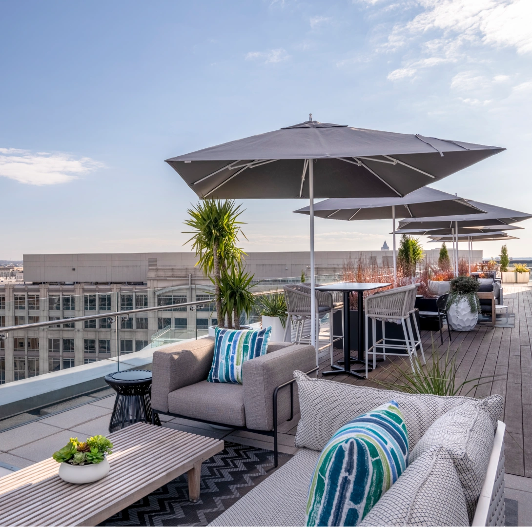 Luxury office building rooftop amenity featuring contemporary patio furniture planters and panoramic urban views