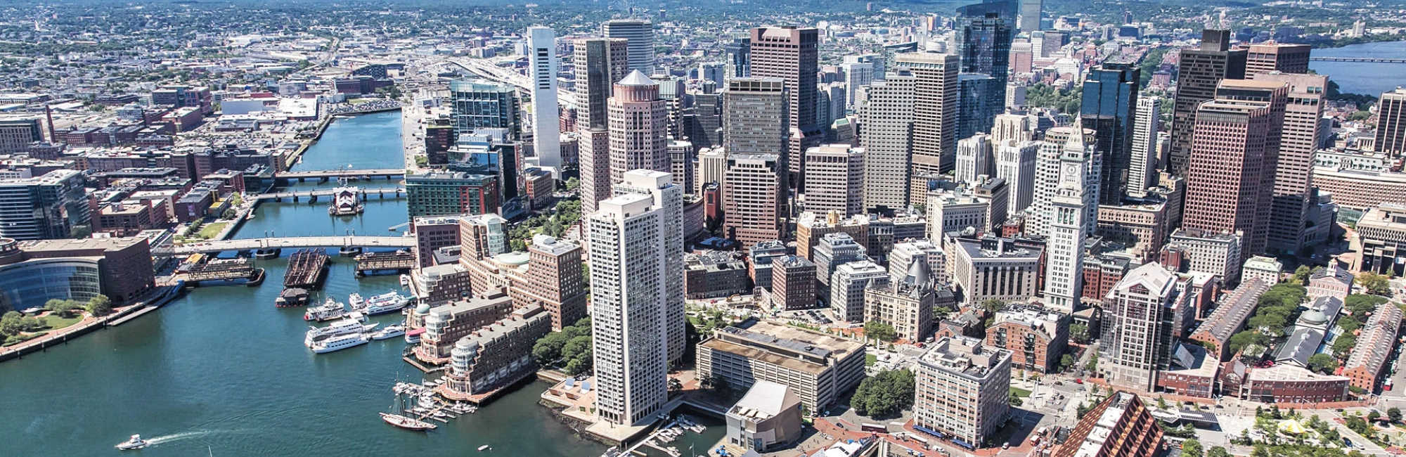 Panoramic aerial of Boston city center featuring historic buildings modern towers and harbor waterways
