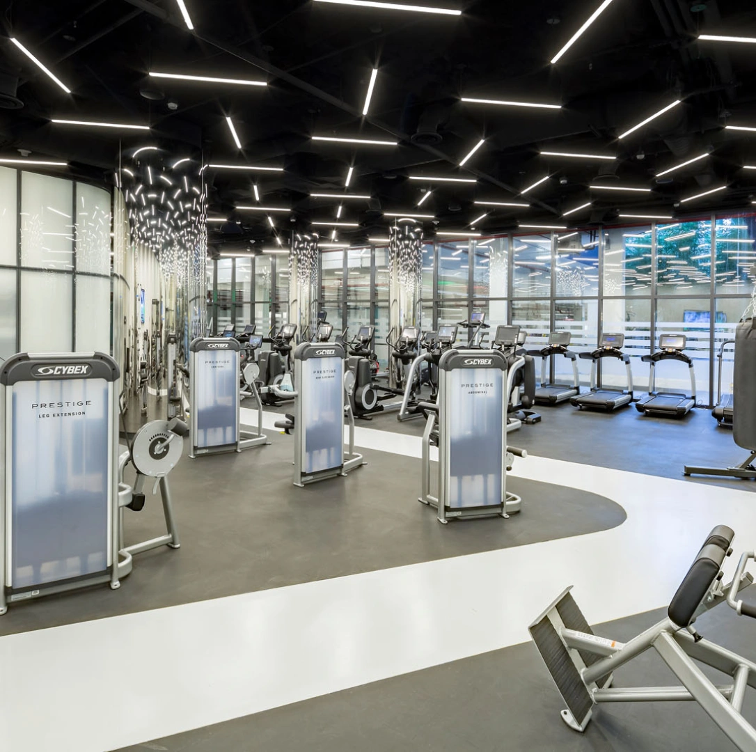 Modern corporate fitness center with strength machines treadmills glass walls and geometric LED lighting