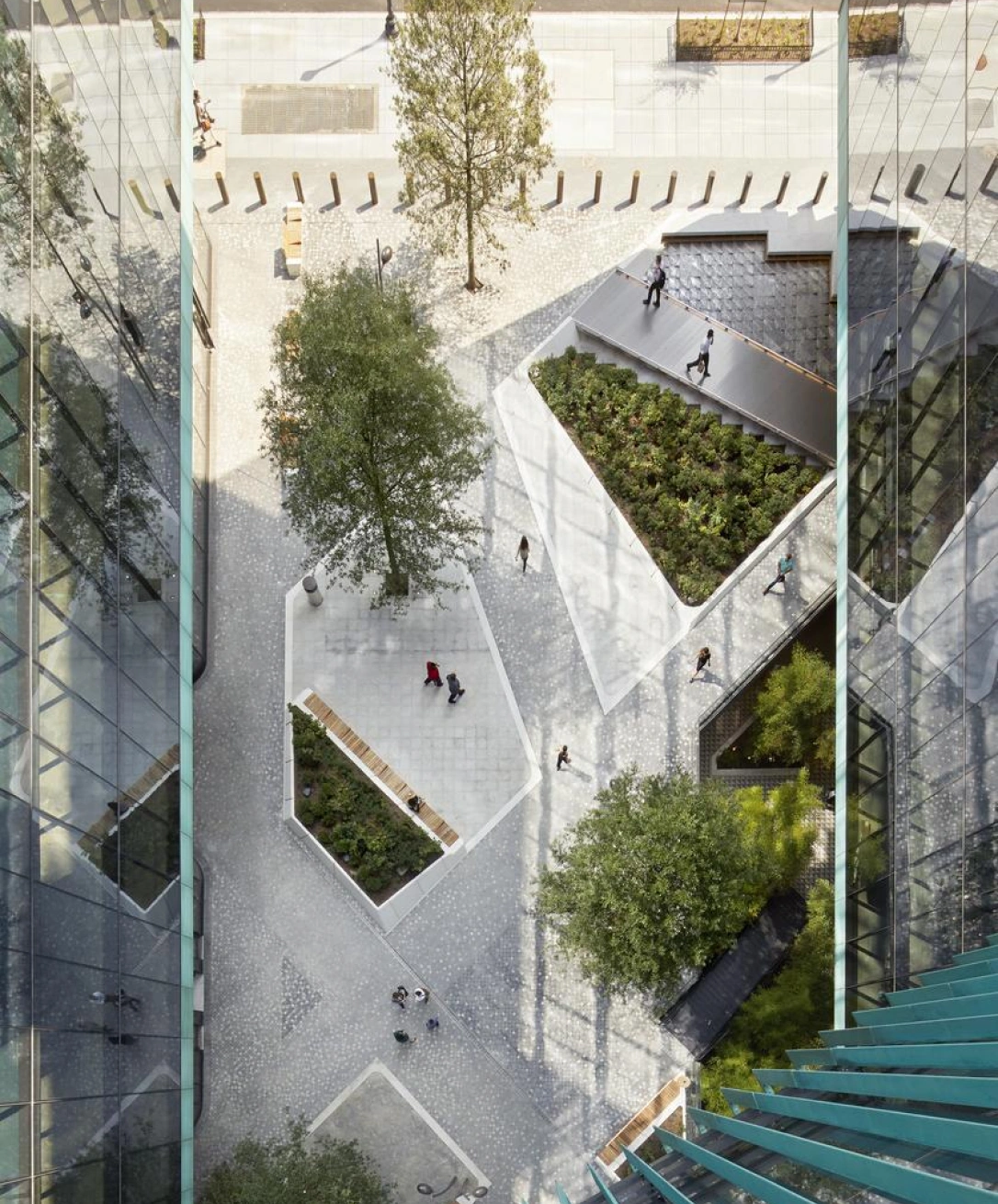 Top-down view of landscaped office plaza featuring geometric paths, greenery, and pedestrian activity