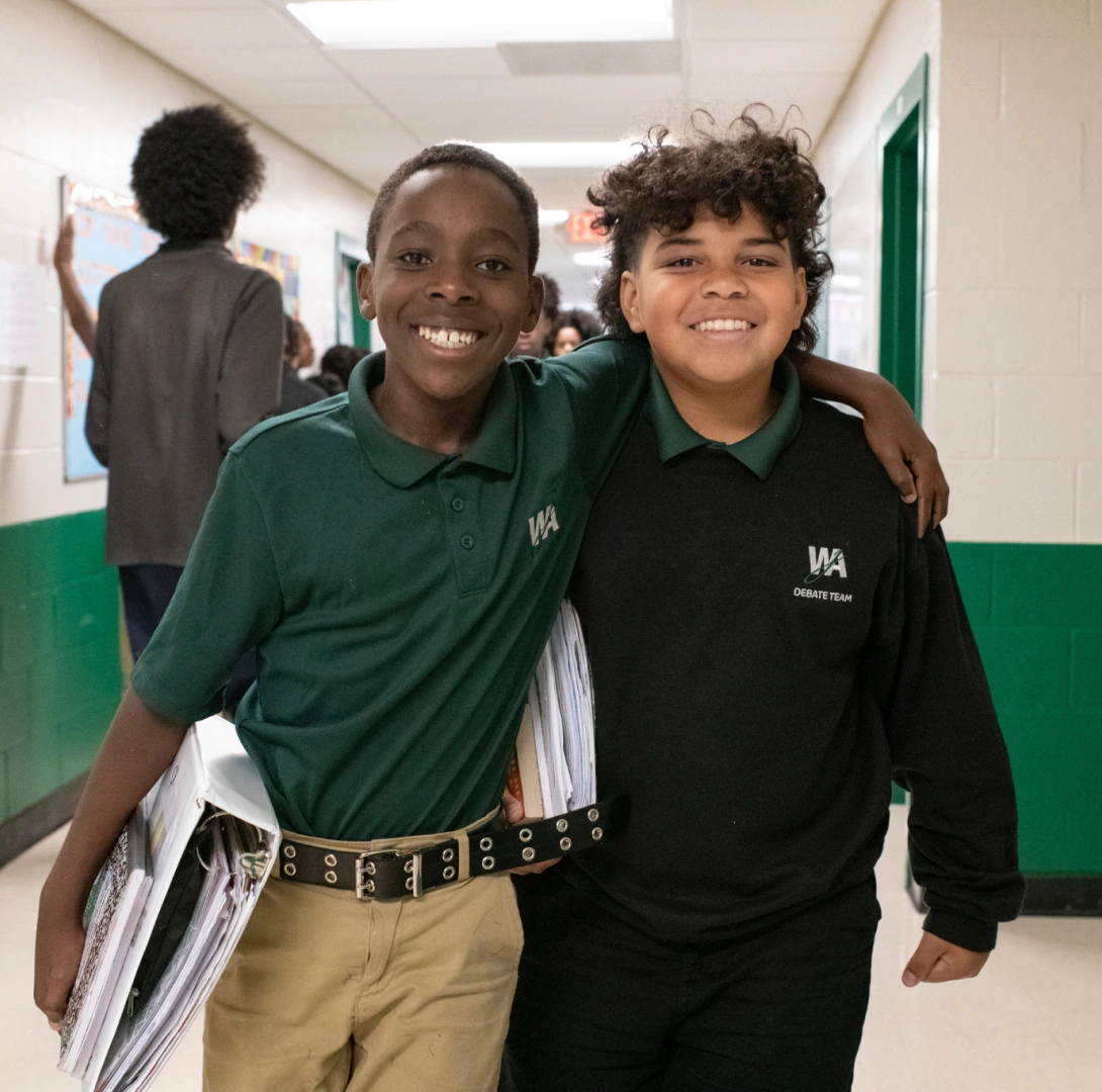 Friends walking through school corridor wearing uniforms and carrying binders between classes