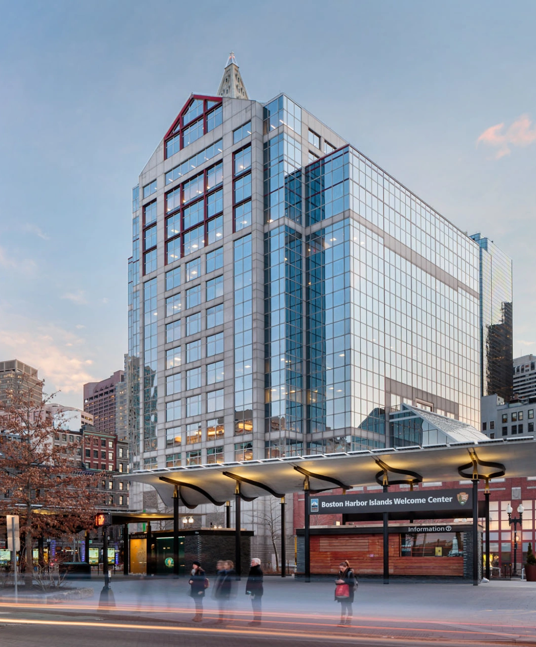 Contemporary urban office building exterior featuring reflective glass facade and city streetscape