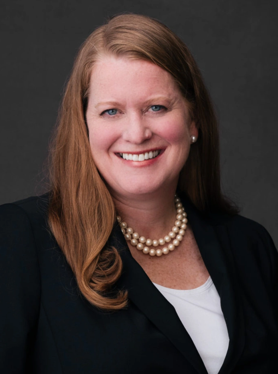Corporate portrait featuring confident professional woman with red hair against neutral studio background