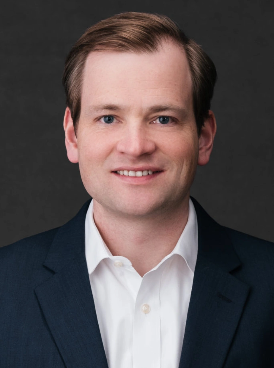 Corporate leadership portrait featuring confident professional man with friendly expression against dark studio background