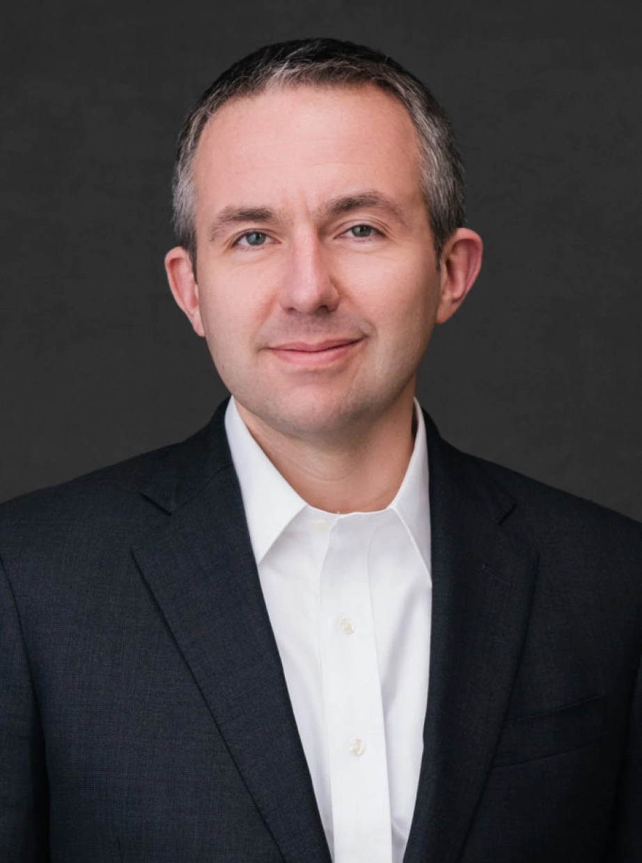 Corporate leadership portrait featuring approachable professional man against neutral studio background