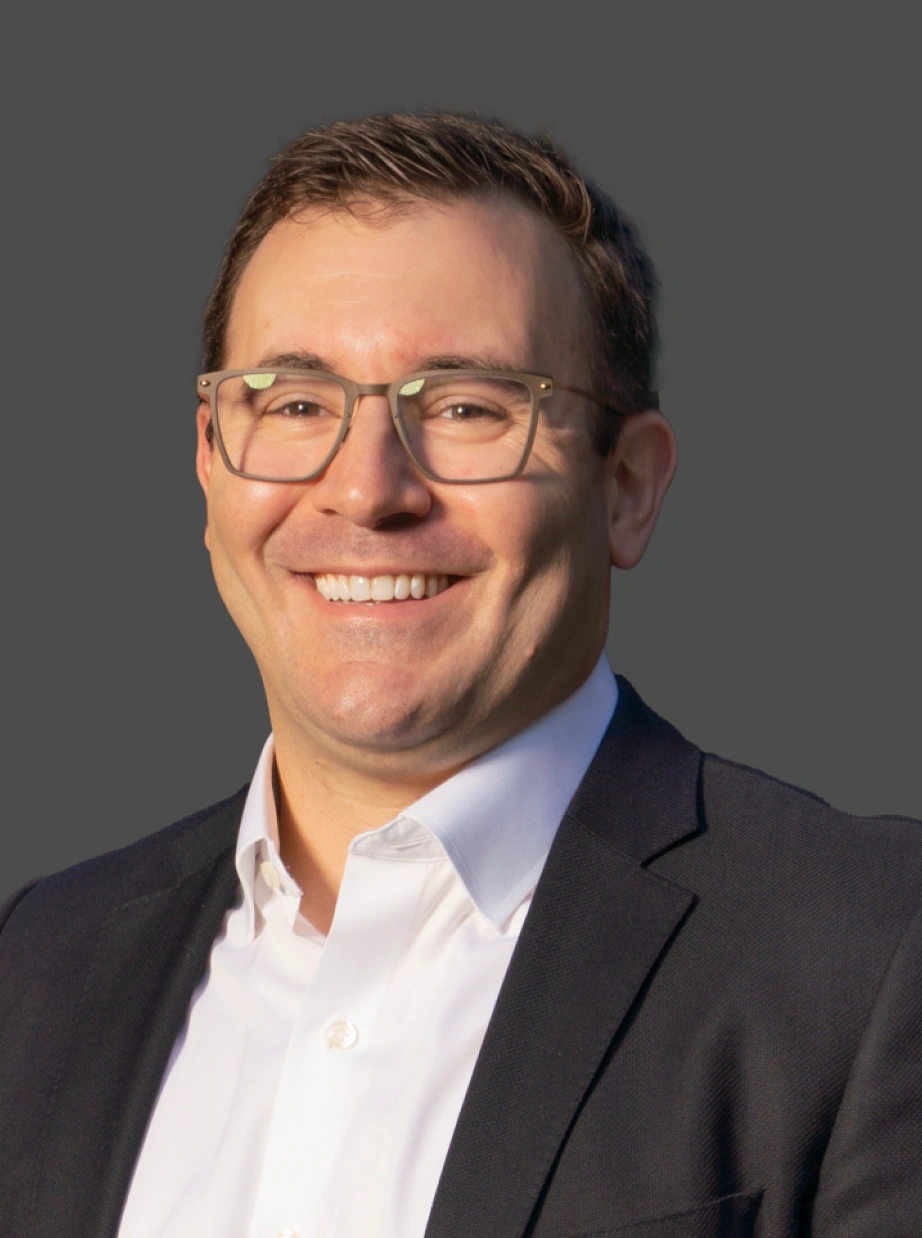 Corporate executive portrait featuring confident professional with glasses against clean neutral background