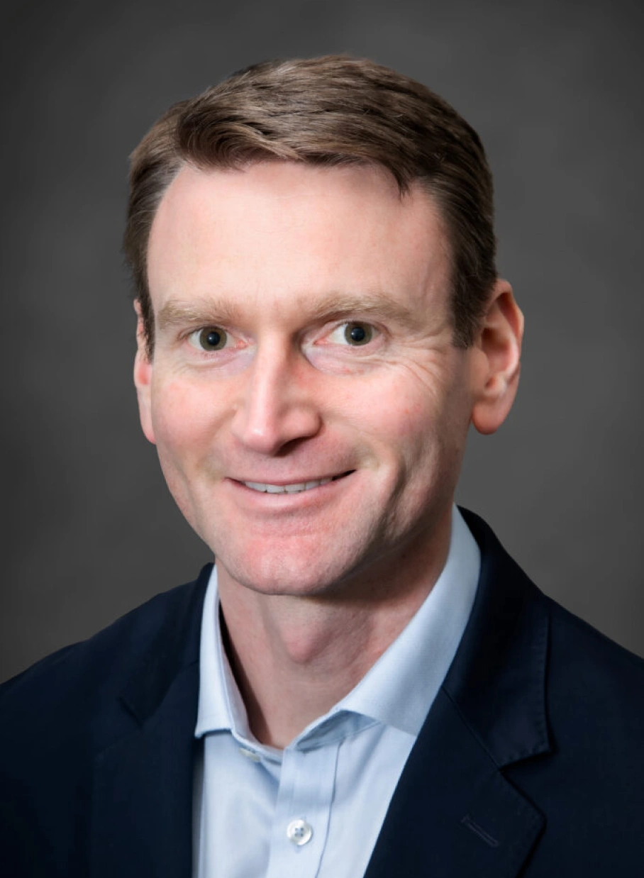 Corporate leadership portrait featuring confident professional man in business attire with friendly expression