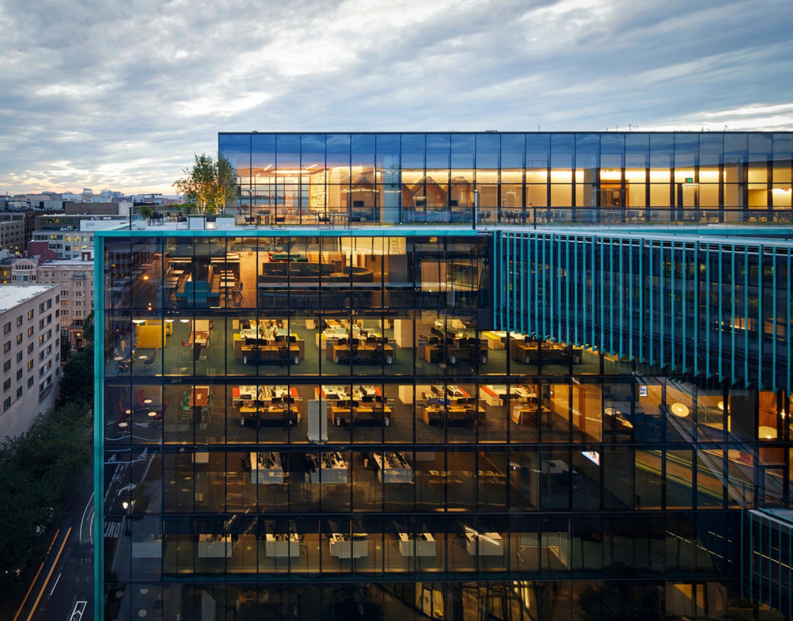 Urban corporate headquarters featuring transparent facade modern design and evening city skyline