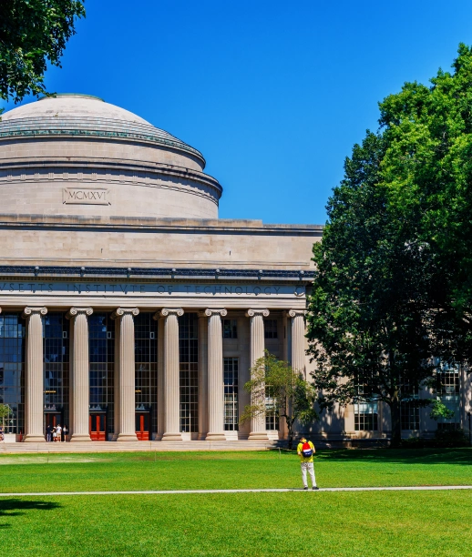Classical university architecture at MIT featuring domed roof, stone columns, and open campus lawn